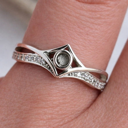 Silver ring with gemstone on a finger against a neutral background