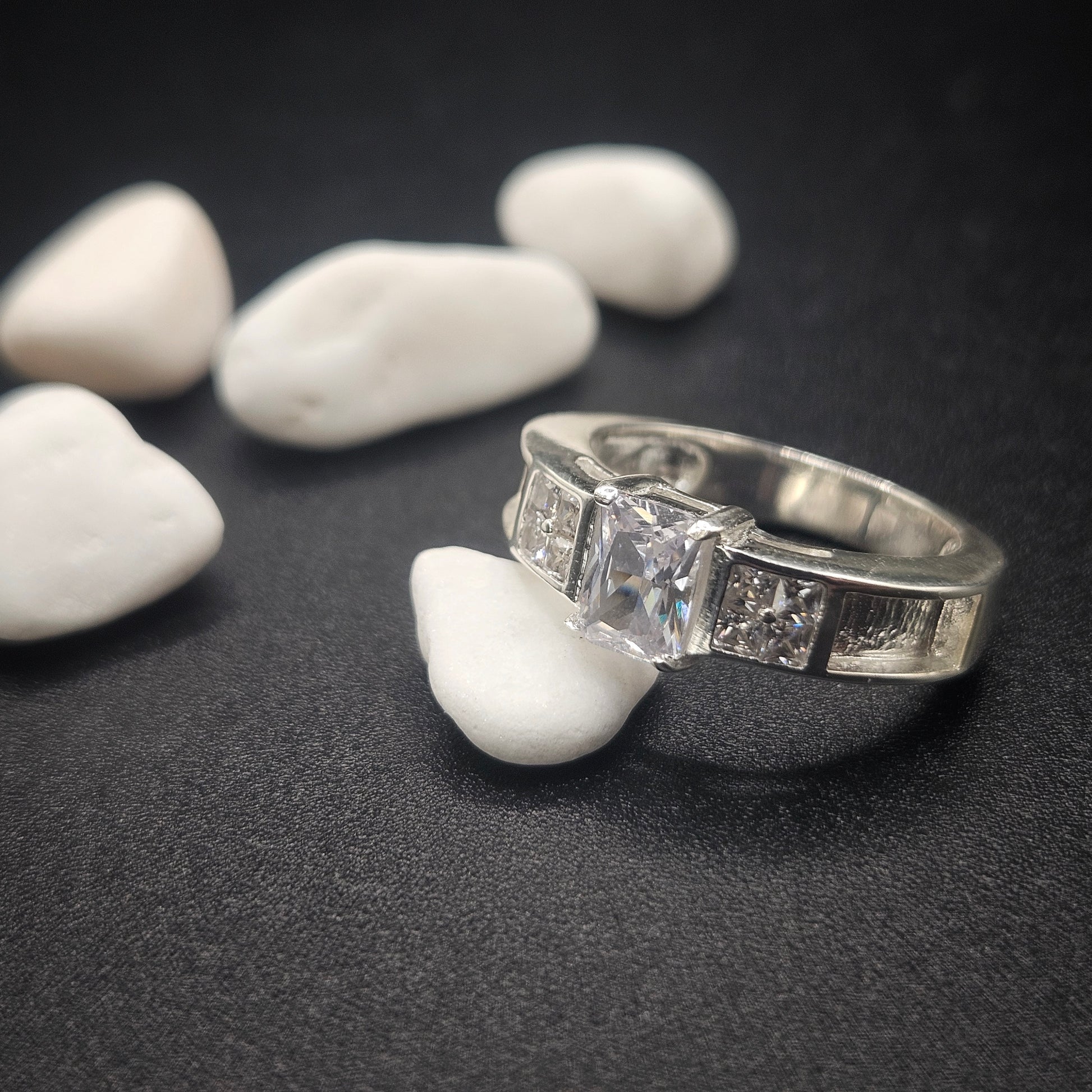 Silver ring with gemstones on a dark surface with white stones