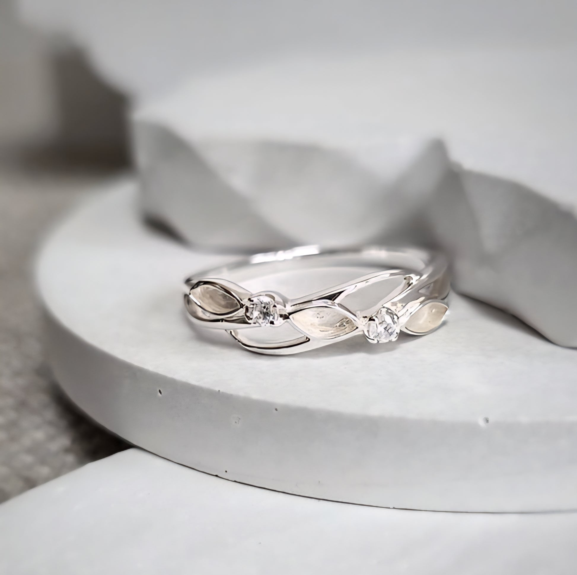 Silver ring with leaf design on a white surface