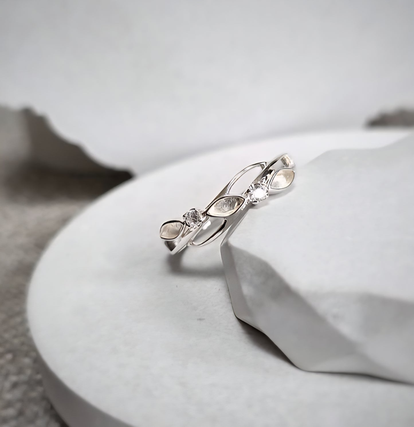 Silver ring with marquise-shaped gemstones on a white surface