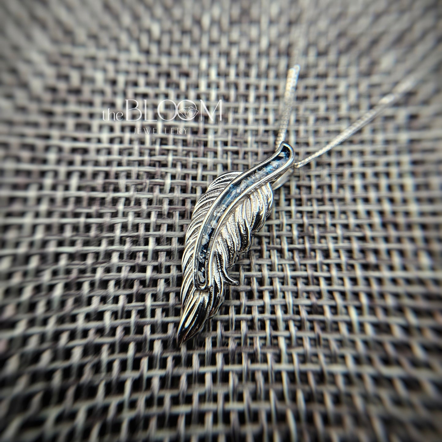 gold feather pendant on a textured surface