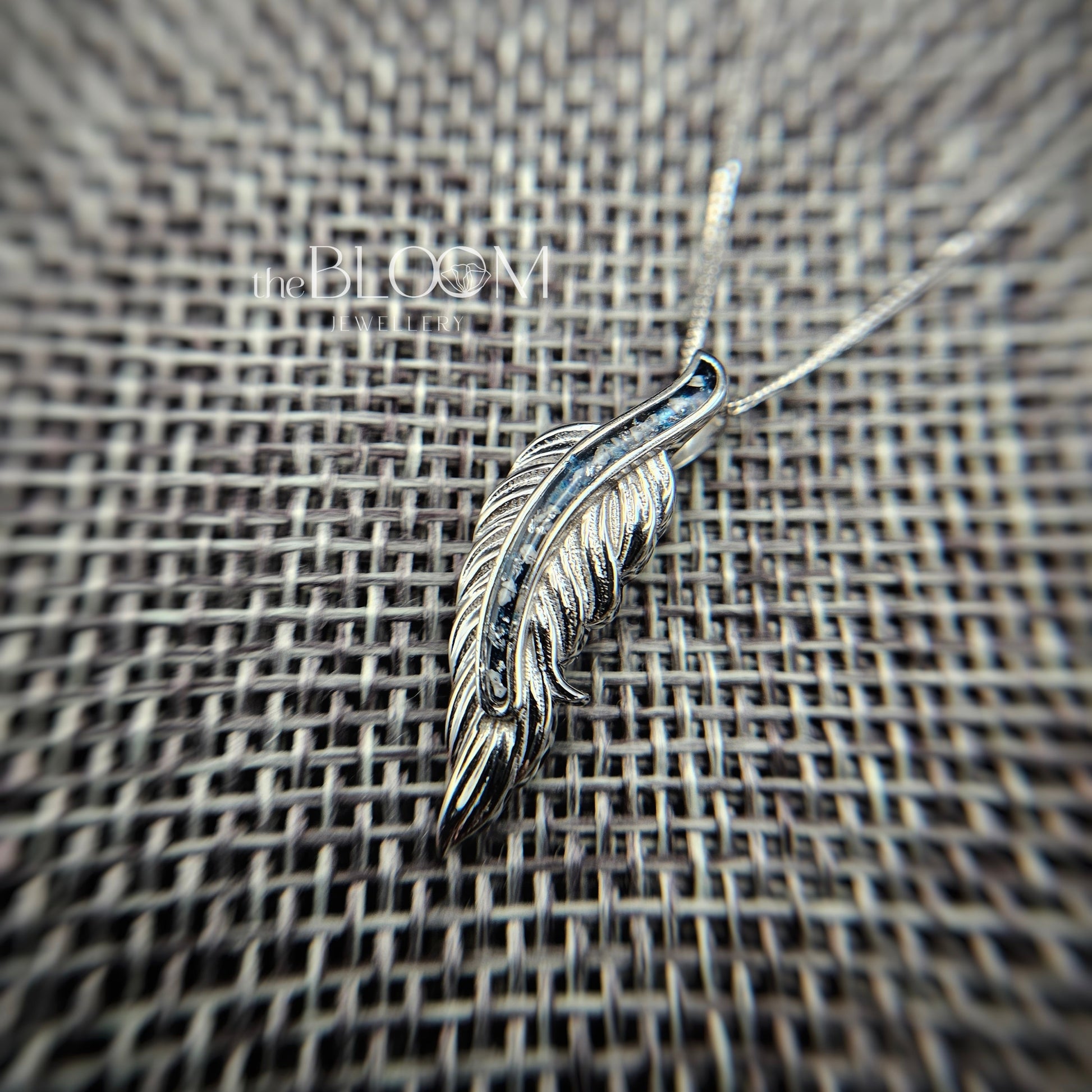 gold feather pendant on a textured surface