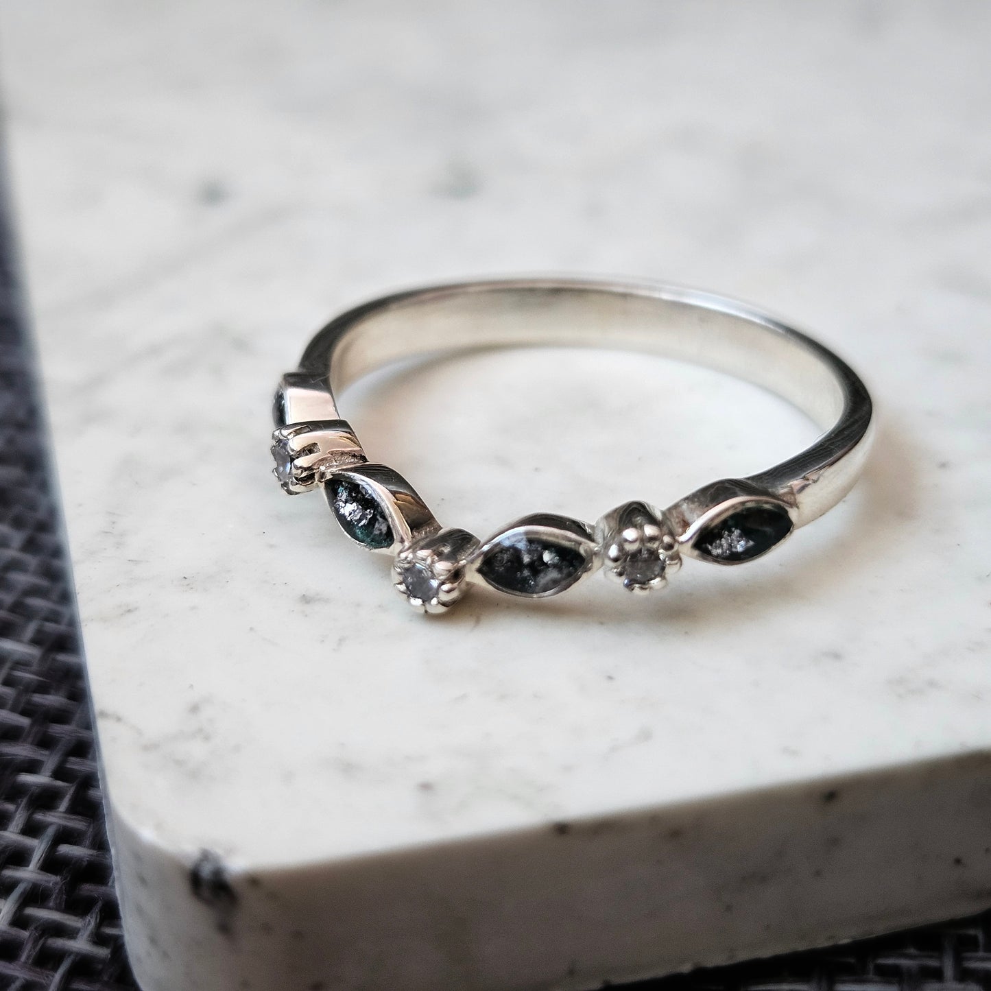 Silver ring with embedded stones on a textured surface