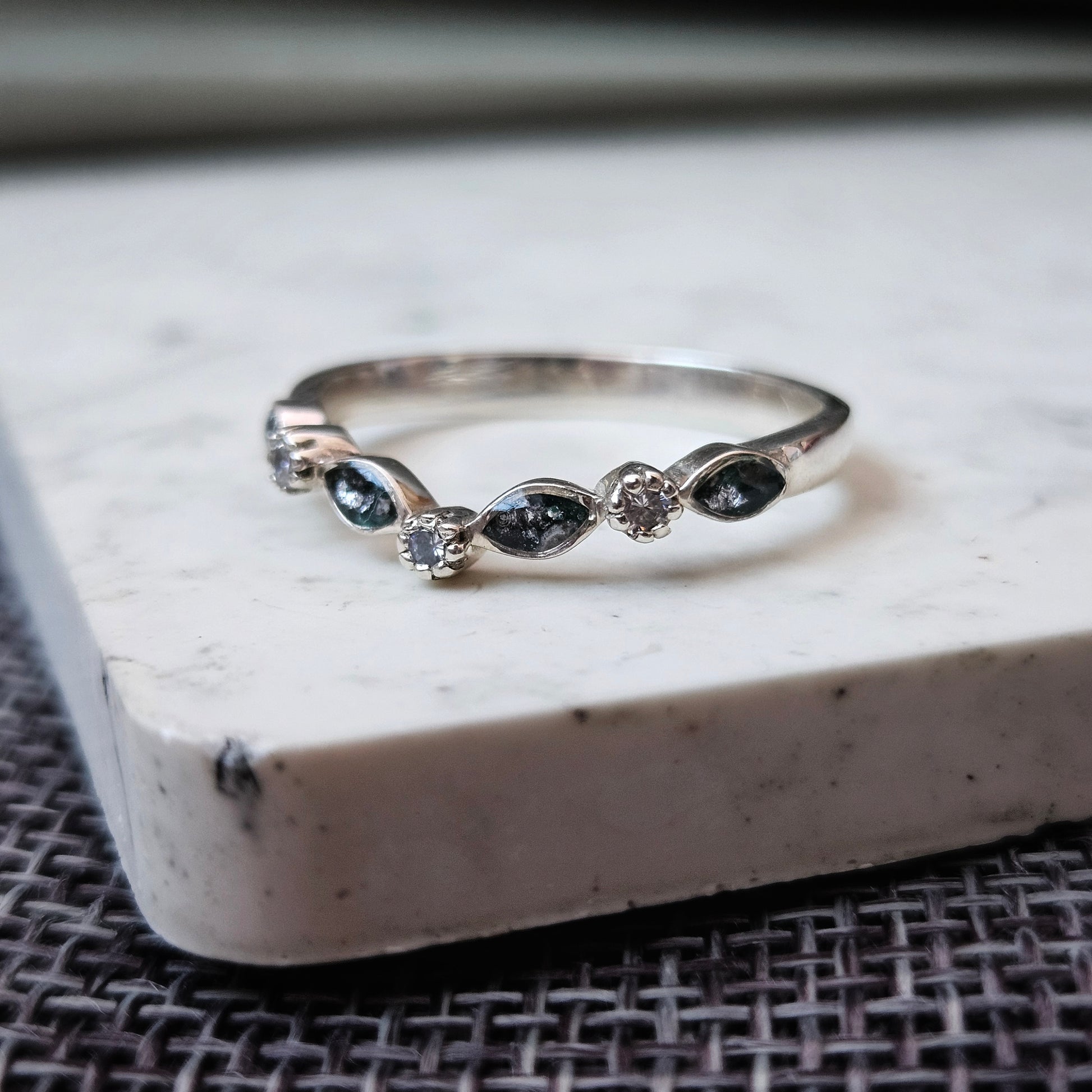 Silver ring with embedded stones on a marble surface