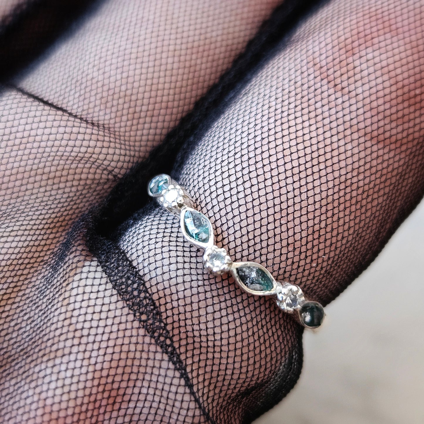 Ring with gemstones on a black mesh background