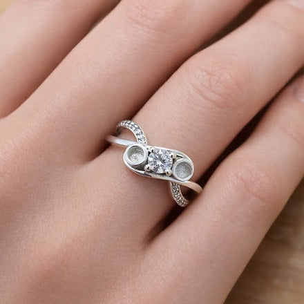 Silver ring with gemstones on a person's finger against a neutral background
