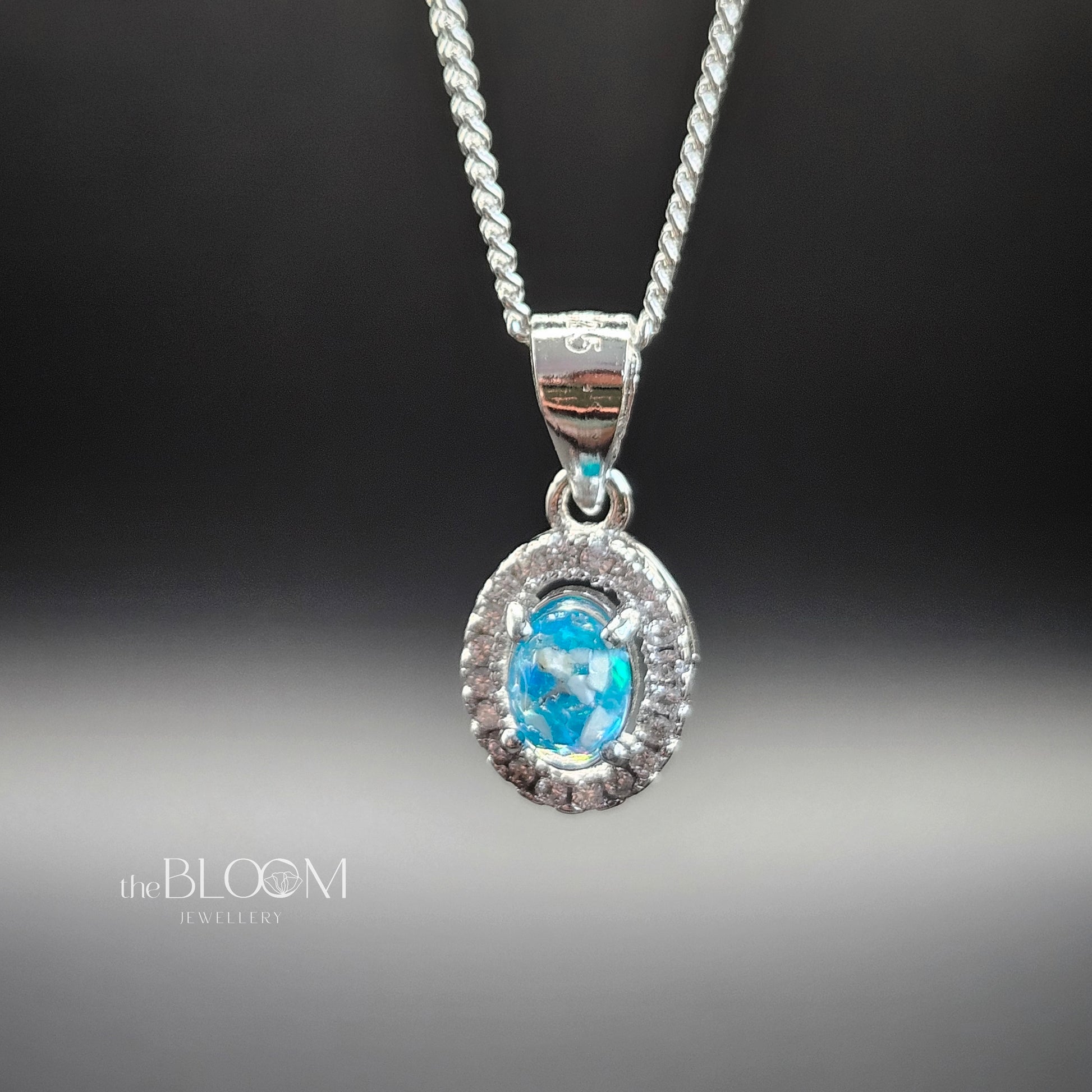 Silver pendant with a blue gemstone on a dark background, branded 'the BLOOM Jewellery'.