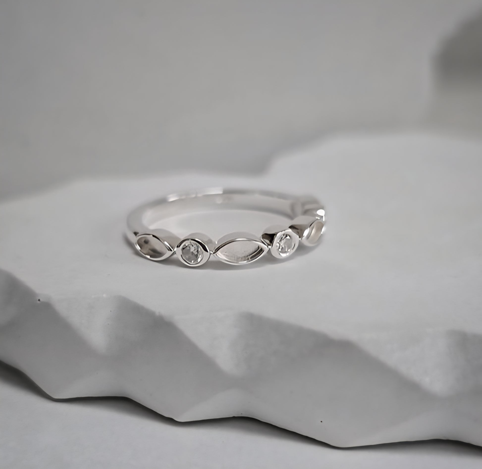 Silver ring with small diamonds on a textured gray surface