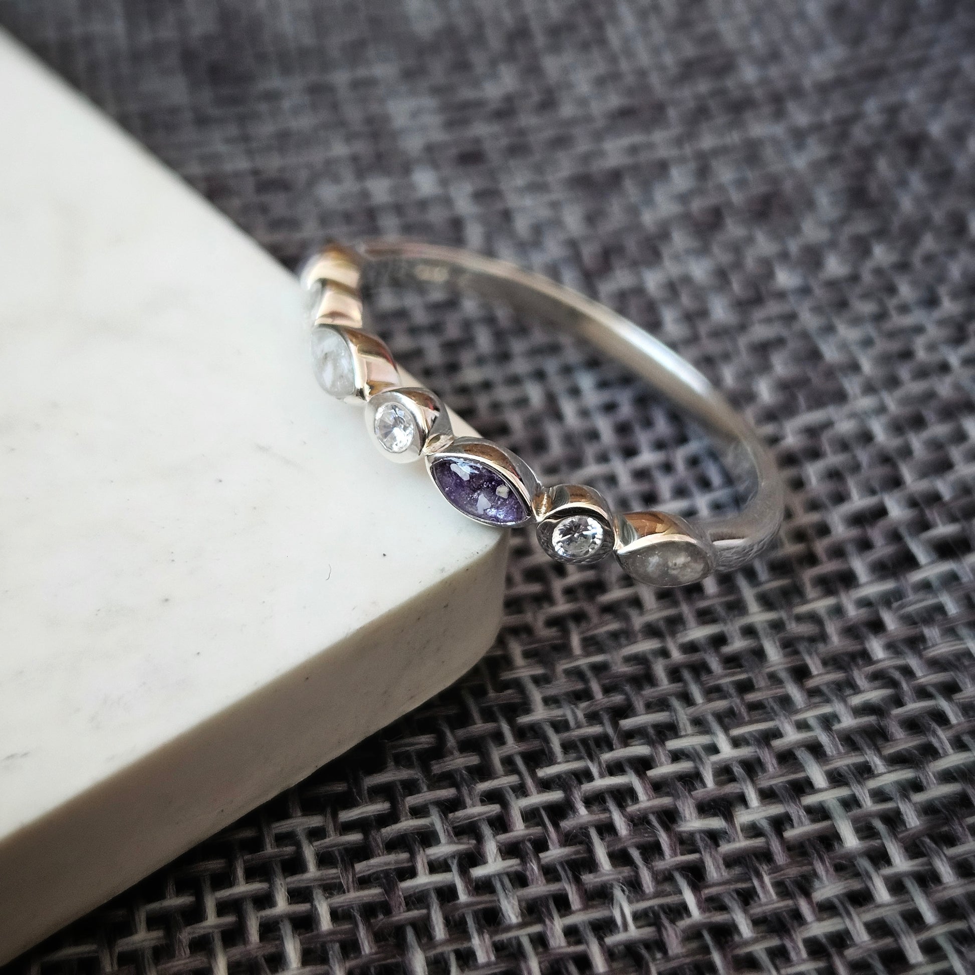Silver ring with a purple gemstone on a textured surface