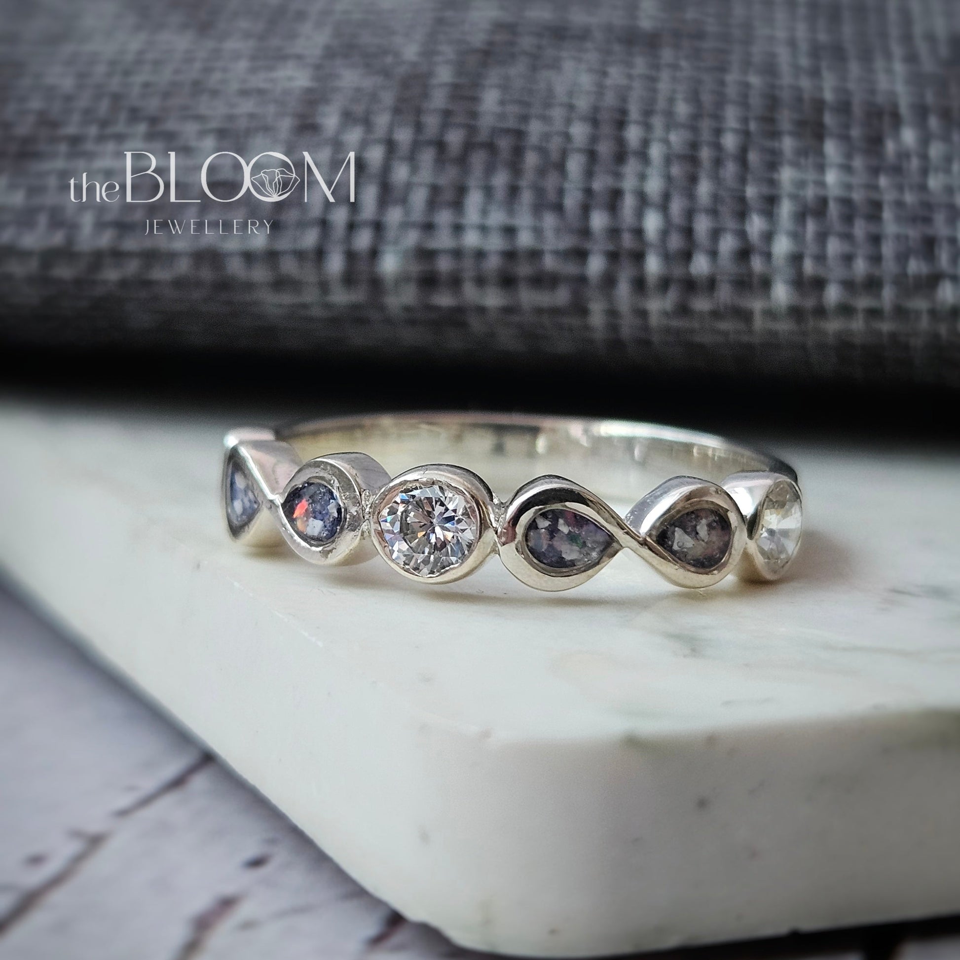 Silver ring with gemstones on a marble surface with a blurred background