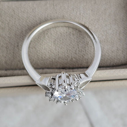 Silver ring with a diamond on a beige surface
