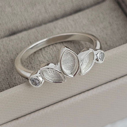 Silver ring with leaf-shaped stones on a gray fabric background