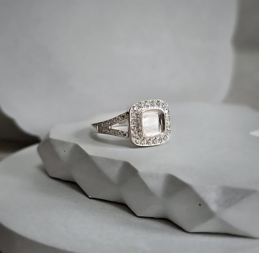 Silver ring with a diamond accent on a textured gray surface