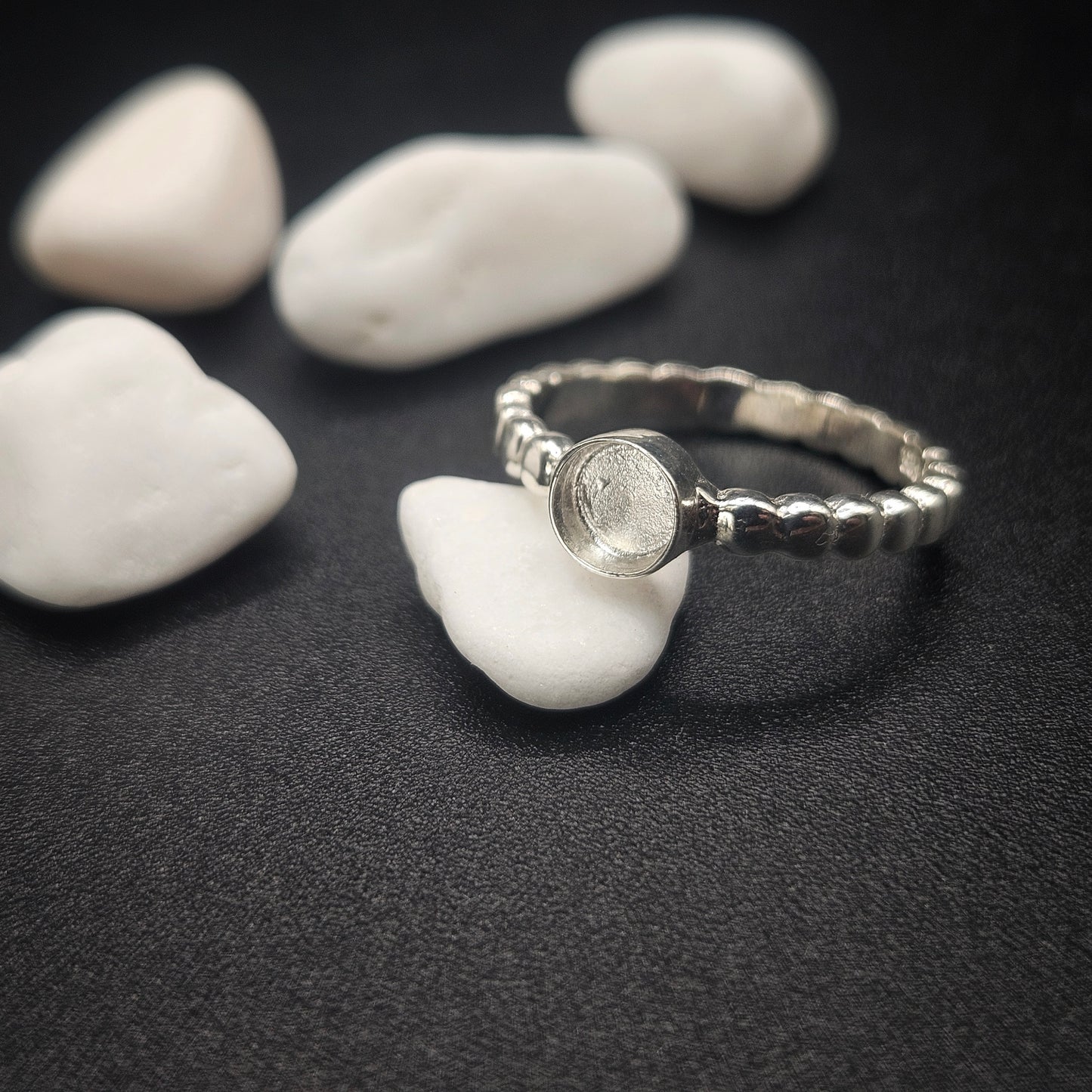 Silver ring with a stone on a dark surface with white stones
