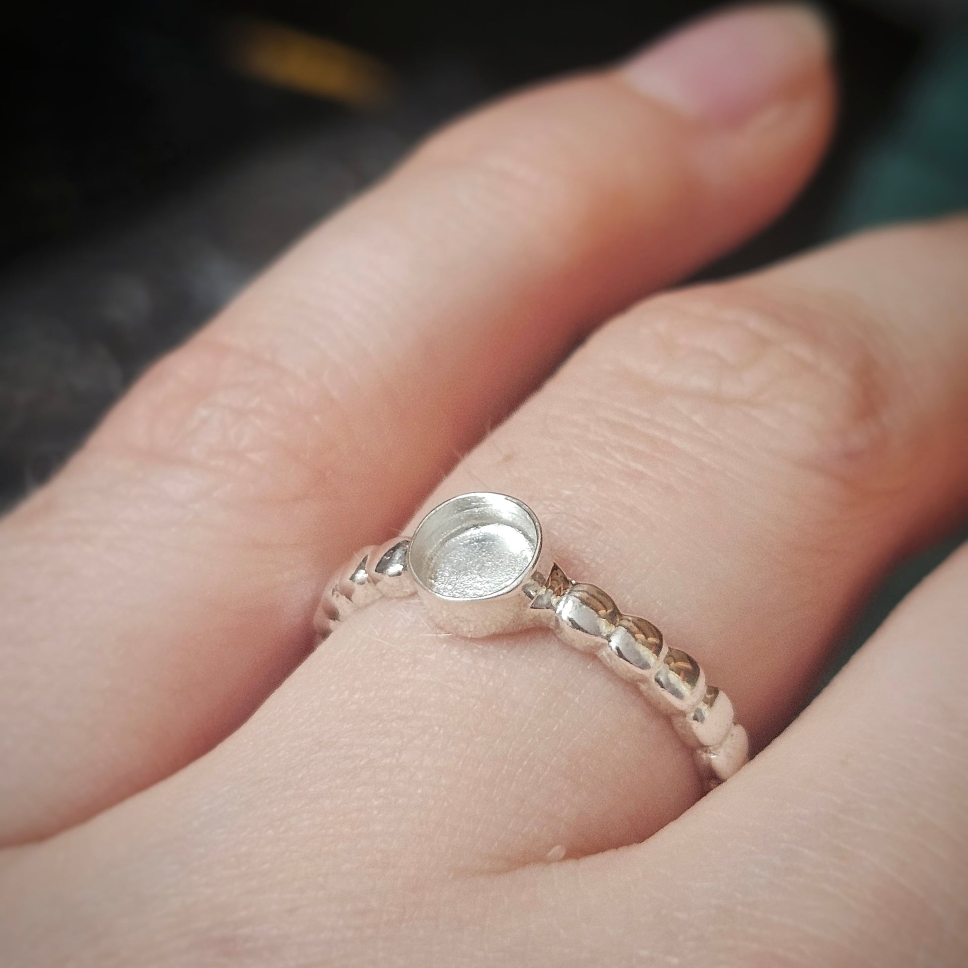 Silver ring on a finger with a blurred background