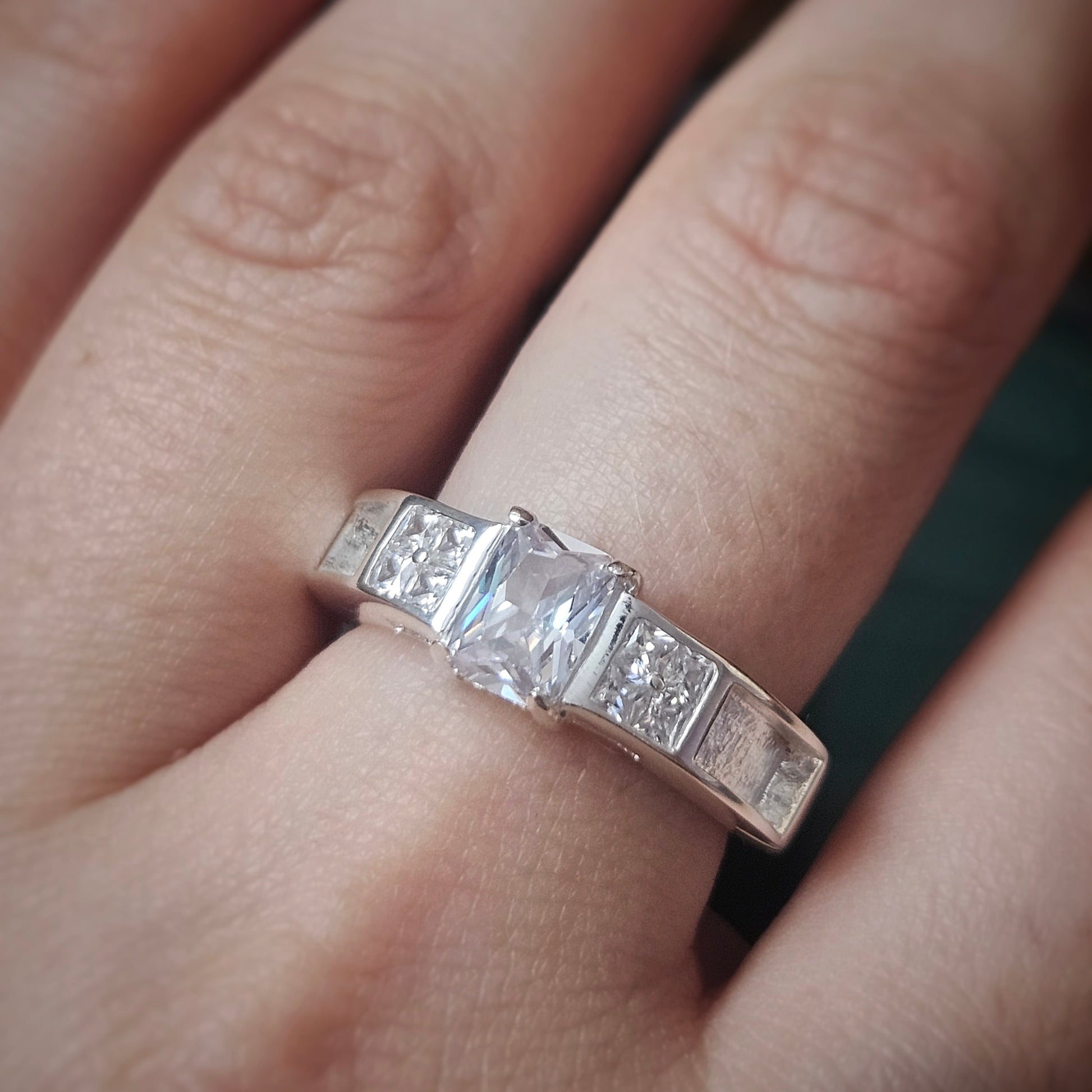 Silver ring with a central diamond on a finger