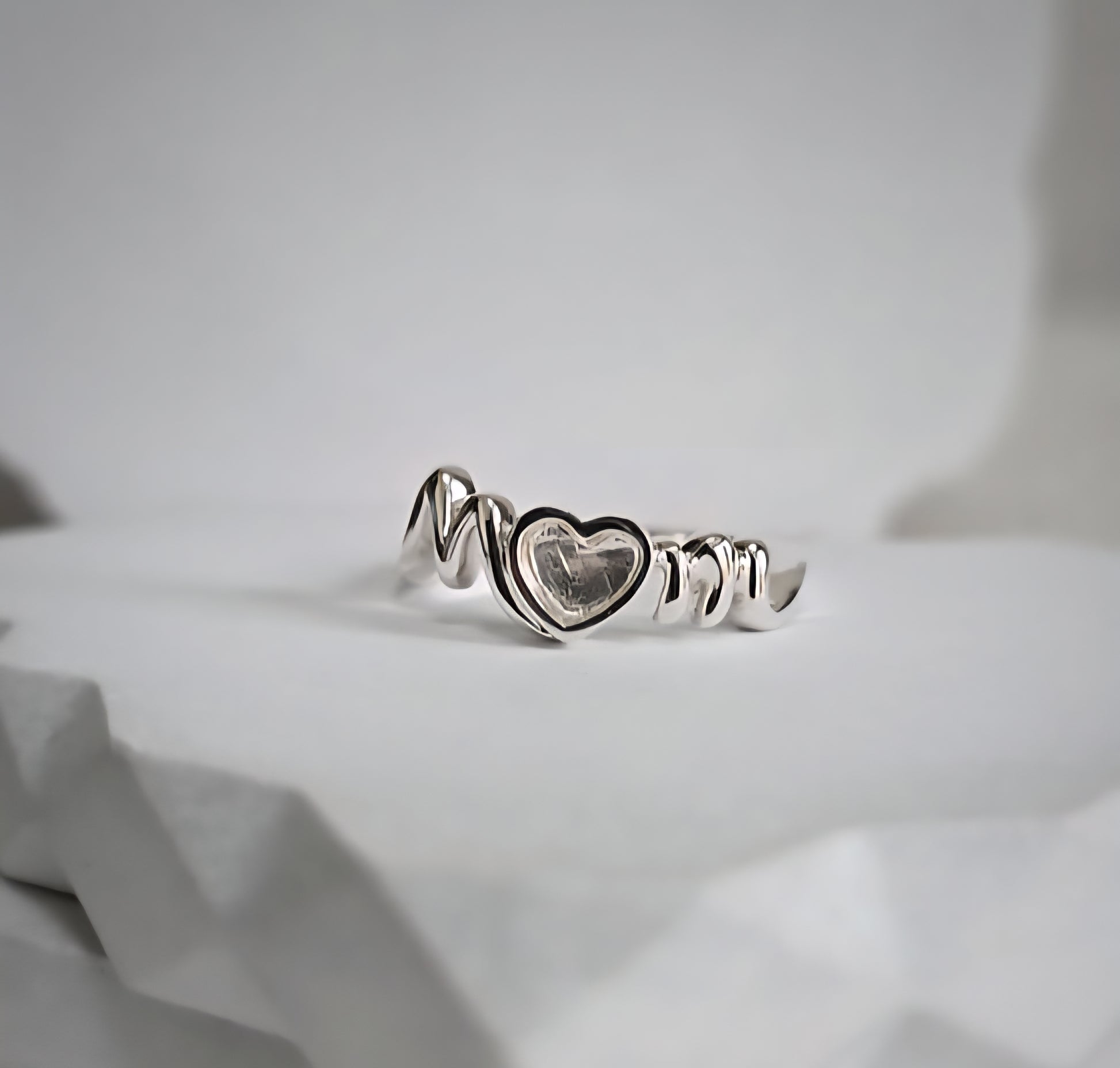 Silver ring with a heart design on a light gray background