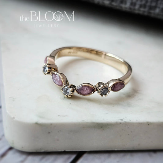 Gold ring with purple gemstones on a marble surface, branded 'the BLOOM'.
