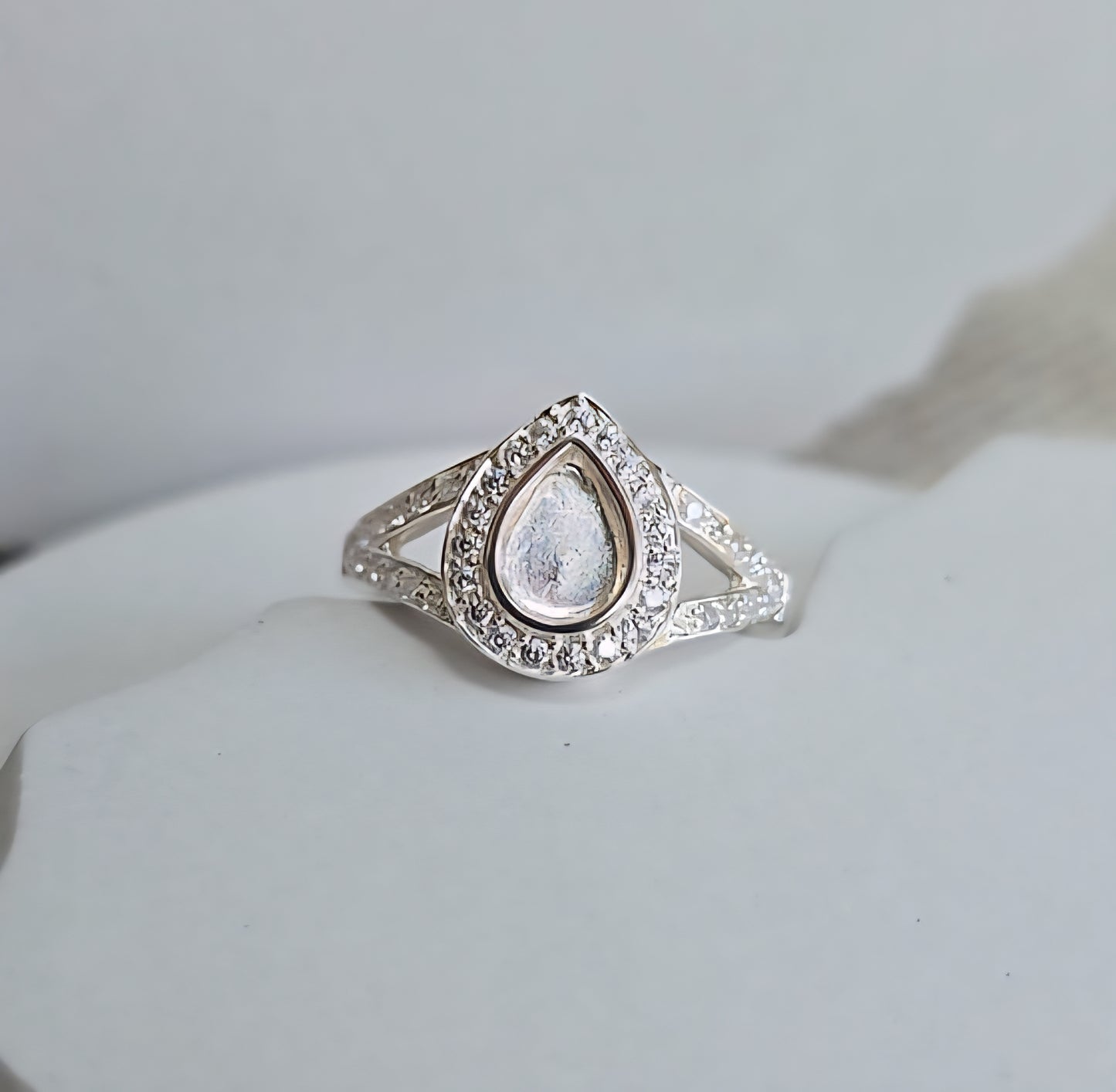 Silver ring with a teardrop-shaped gemstone on a light gray background