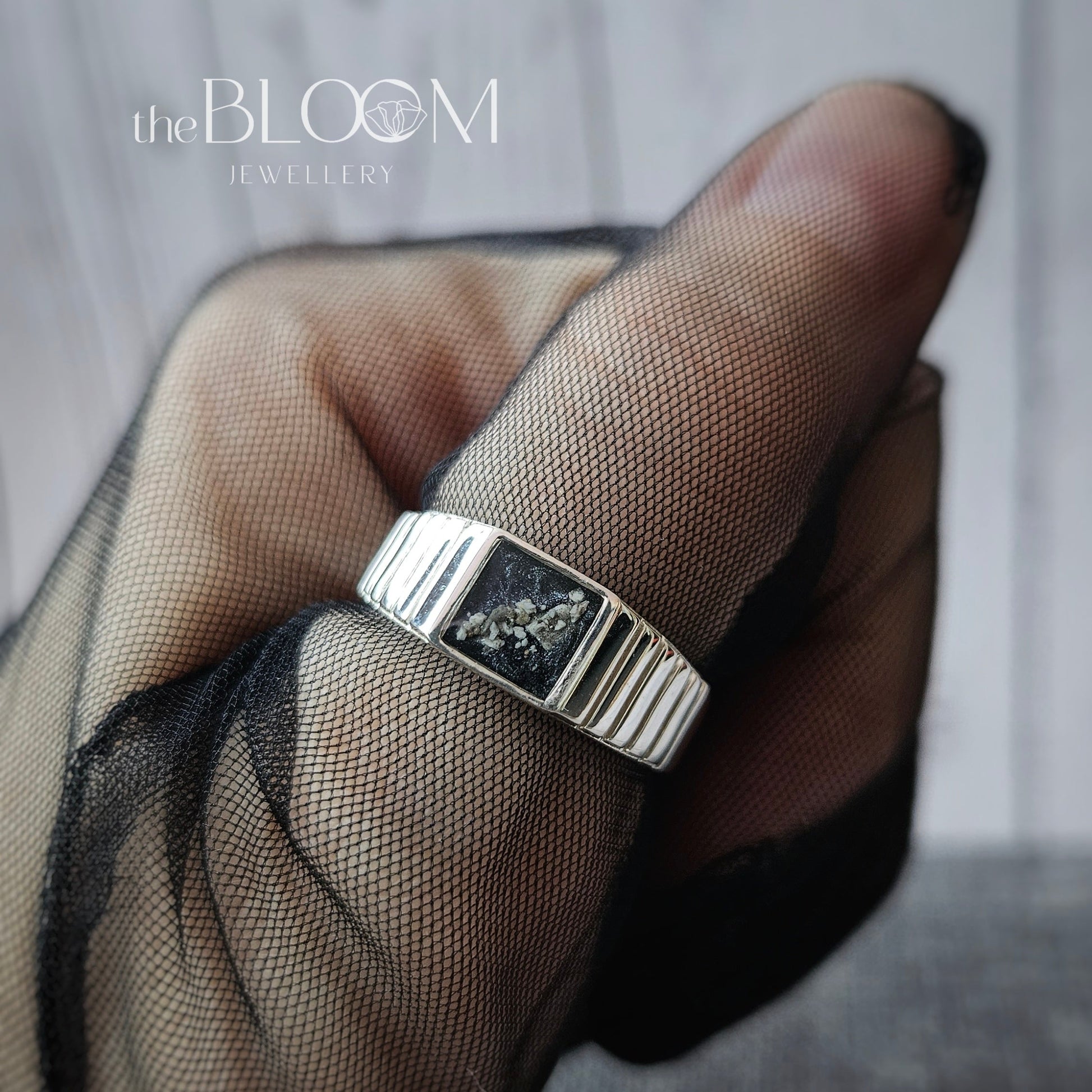 Silver ring on a finger with 'the BLOOM' branding in the corner.