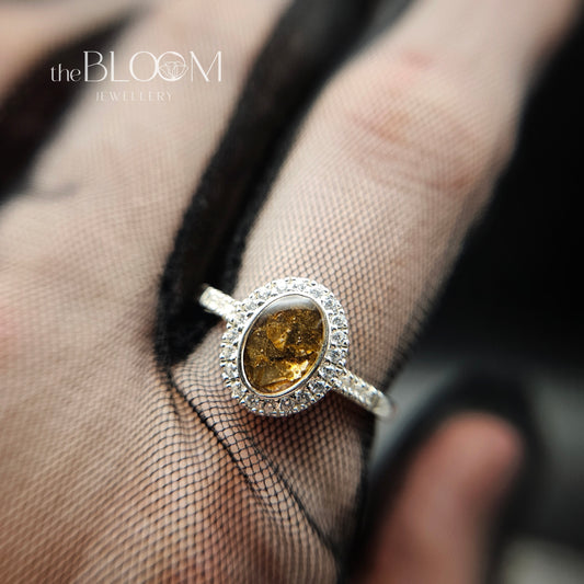 Silver ring with a yellow gemstone on a hand wearing a sheer glove.