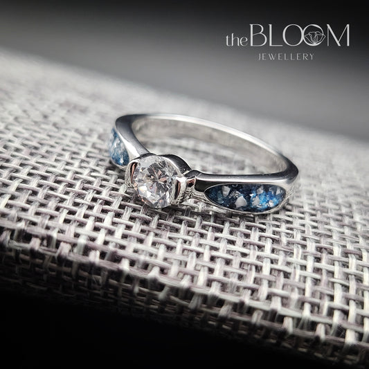 Silver ring with a diamond on a textured surface, branded 'the BLOOM Jewellery'.