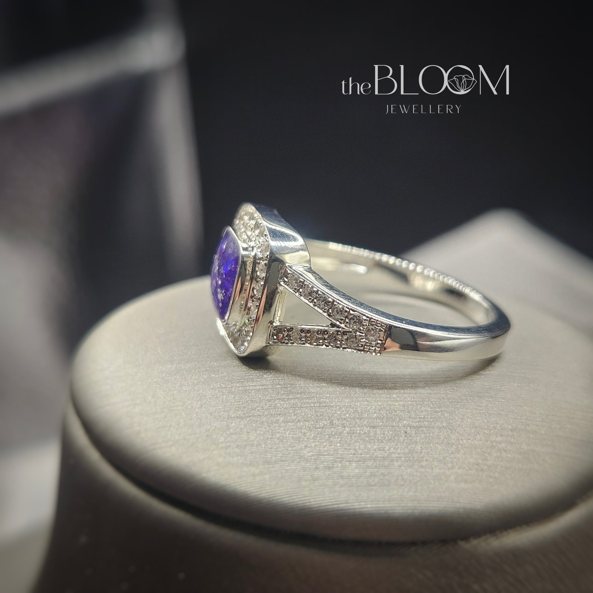 Silver ring with a purple gemstone on a dark background, featuring 'the Bloom Jewellery' brand.