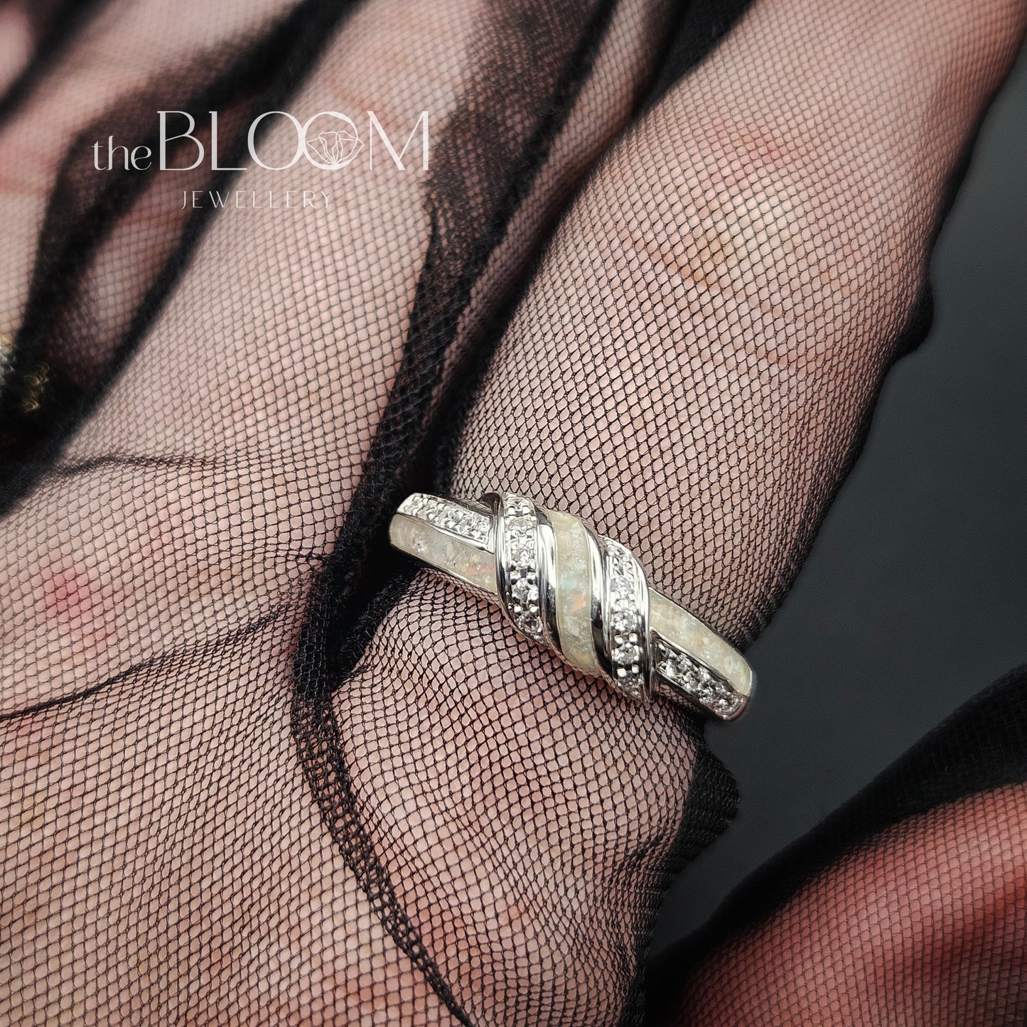 Silver ring on a mesh fabric with 'the BLOOM JEWELRY' logo.