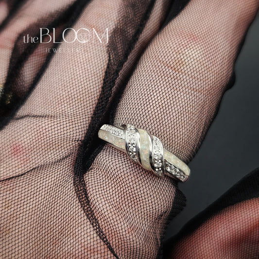 Silver ring on a mesh fabric with 'the BLOOM JEWELRY' logo.