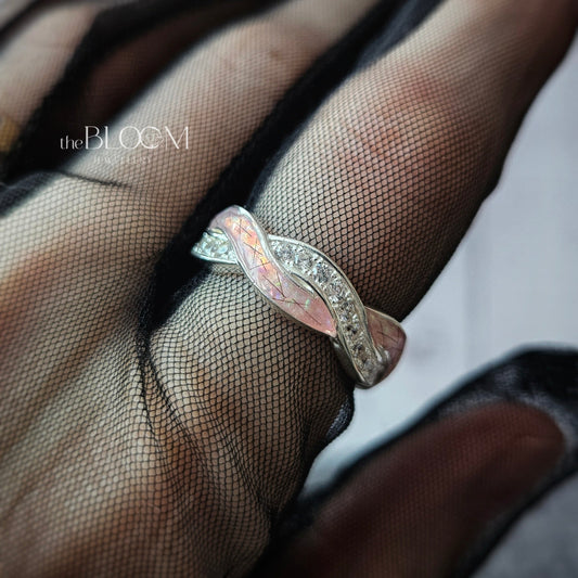 Silver ring with a wavy design on a finger wearing a sheer glove.