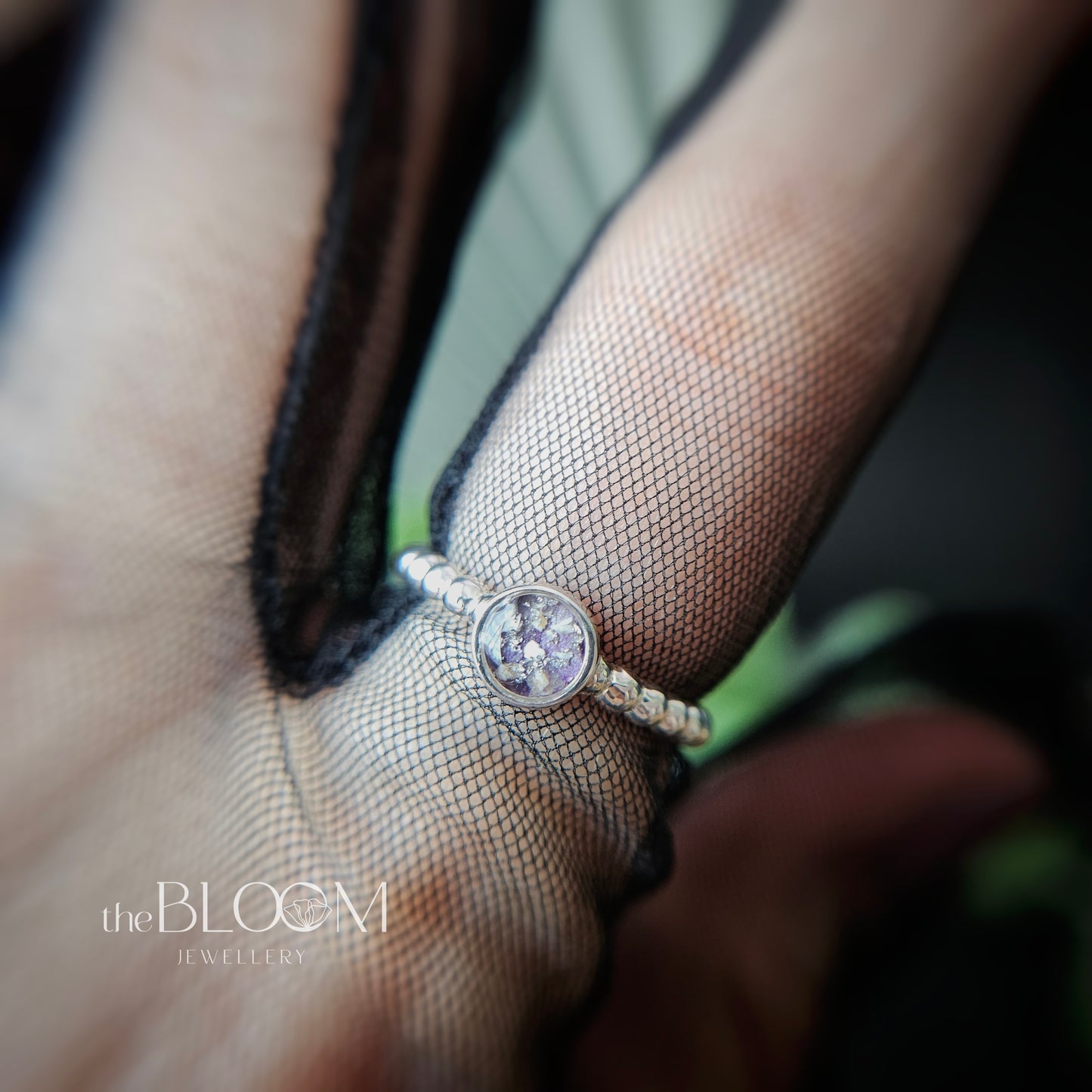 Close-up of a ring on a finger with 'the BLOOM JEWELLERY' branding.