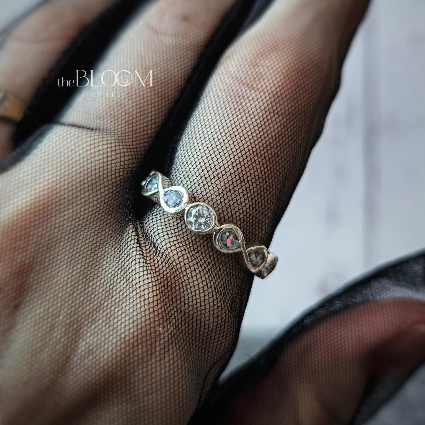 Close-up of a hand wearing a black mesh glove with a silver ring featuring gemstones.