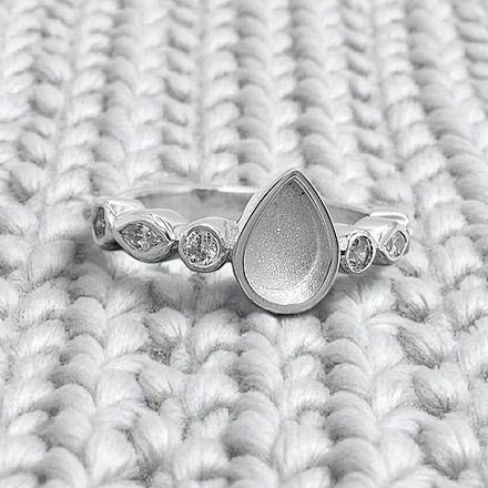 Silver ring with a teardrop-shaped center stone on a textured white background