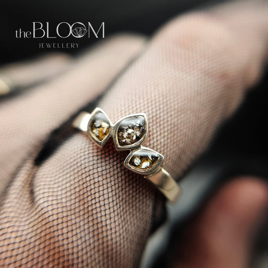 gold ring with gemstones on a hand wearing a sheer glove, branded 'the BLOOM JEWELLERY'.