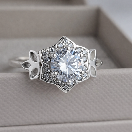 Silver ring with a large diamond and intricate design on a gray surface