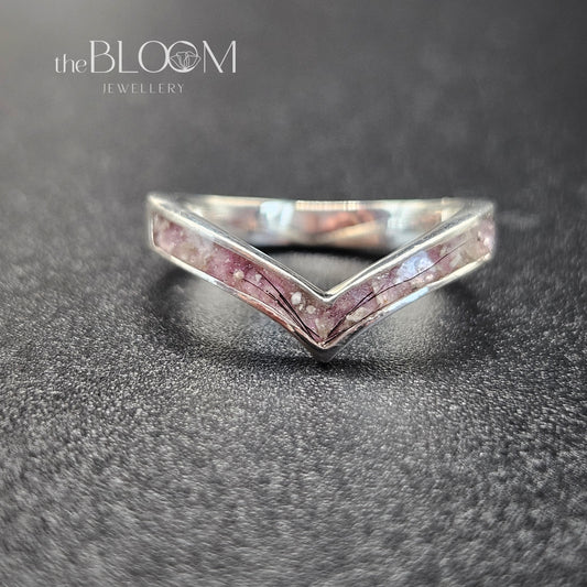 Silver ring with pink gemstones on a dark textured surface, branded 'the BLOOM Jewellery'.
