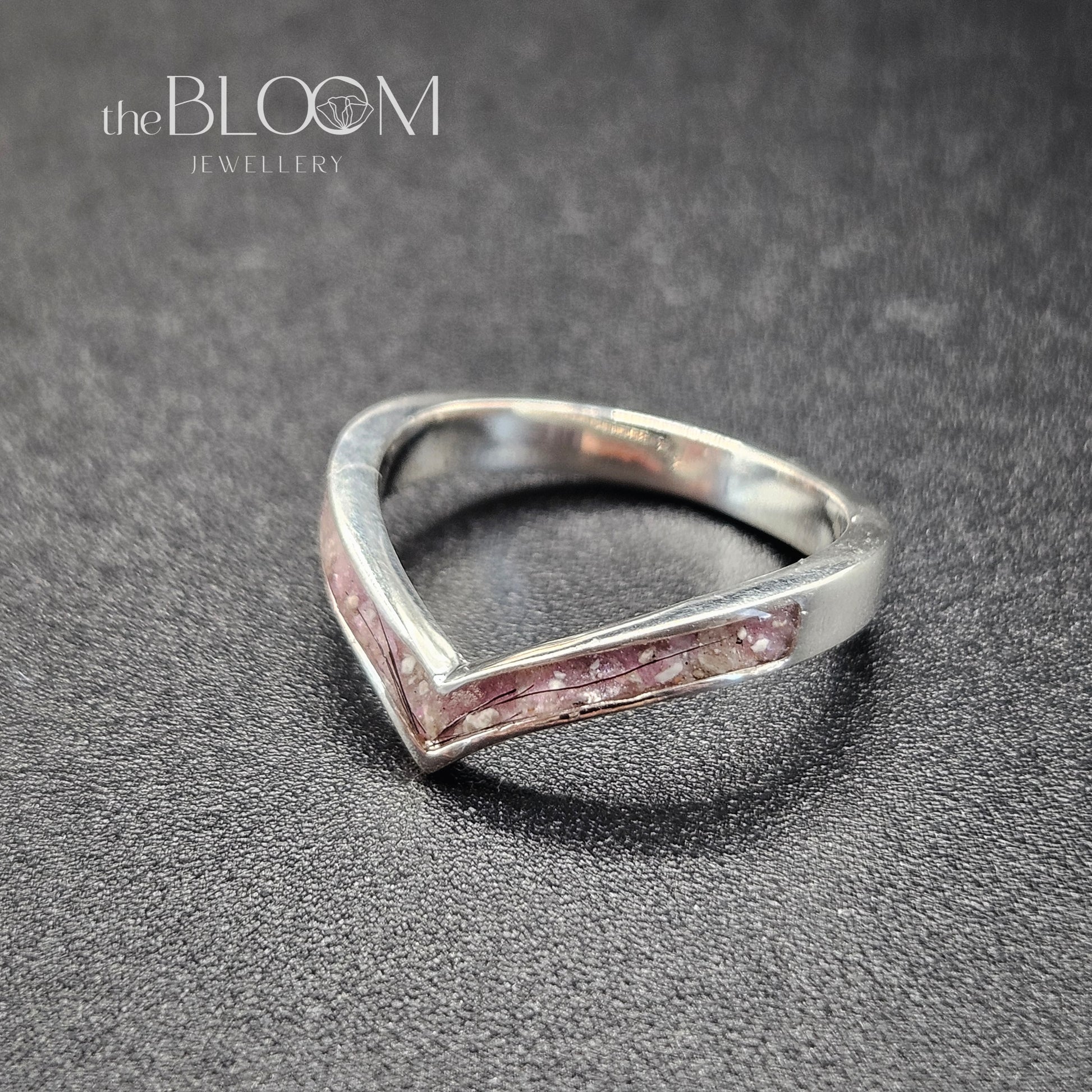 Silver ring with pink interior on a gray surface, branded 'the BLOOM Jewellery'.